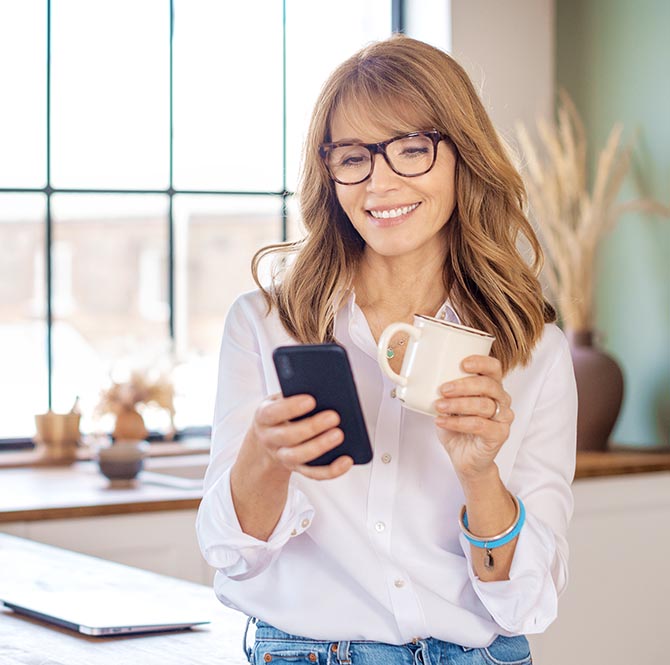 Woman holding mobile phone in kitchen